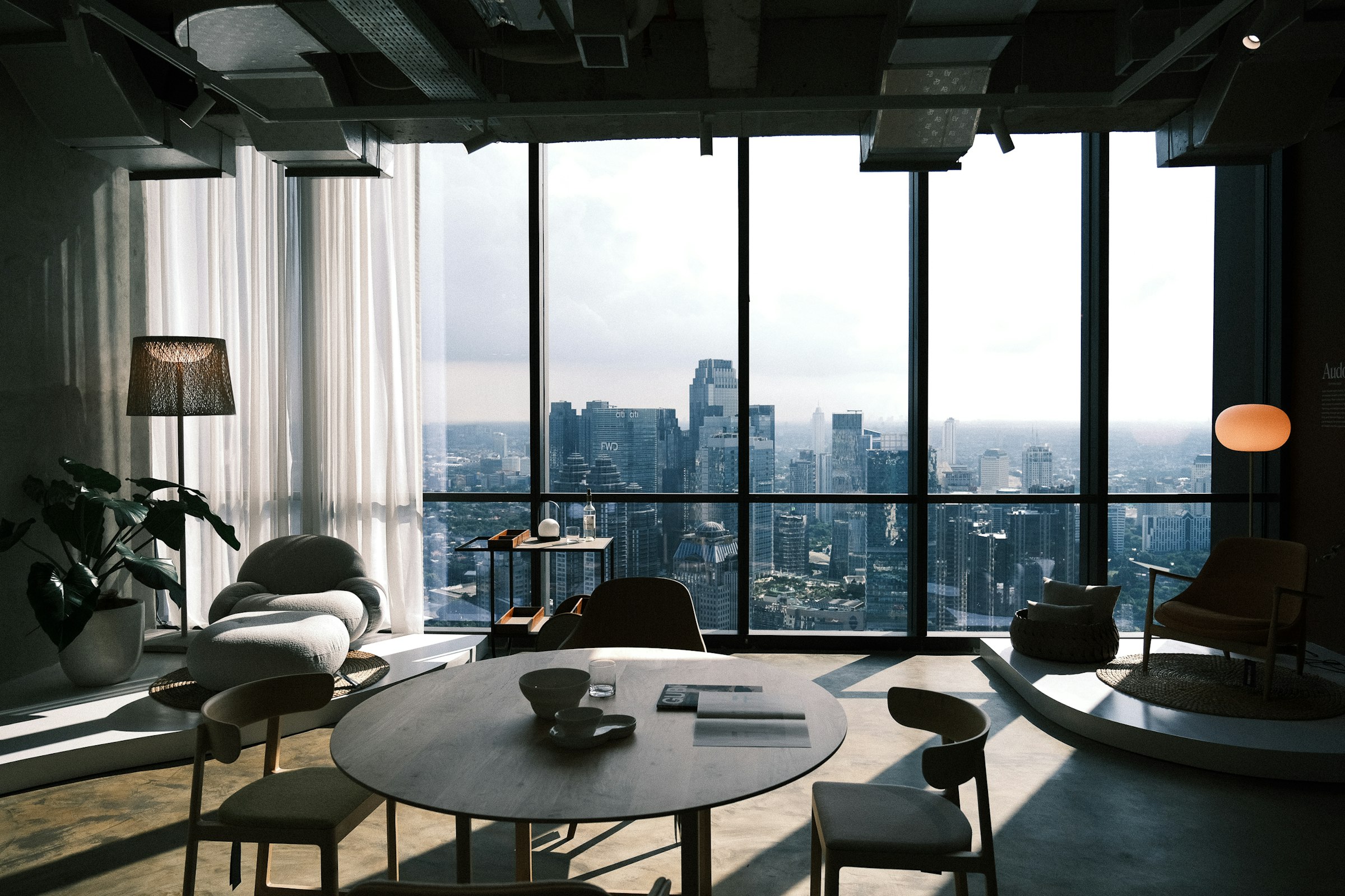 A calm high-rise lounge looking out over a city skyline through floor-to-ceiling glass