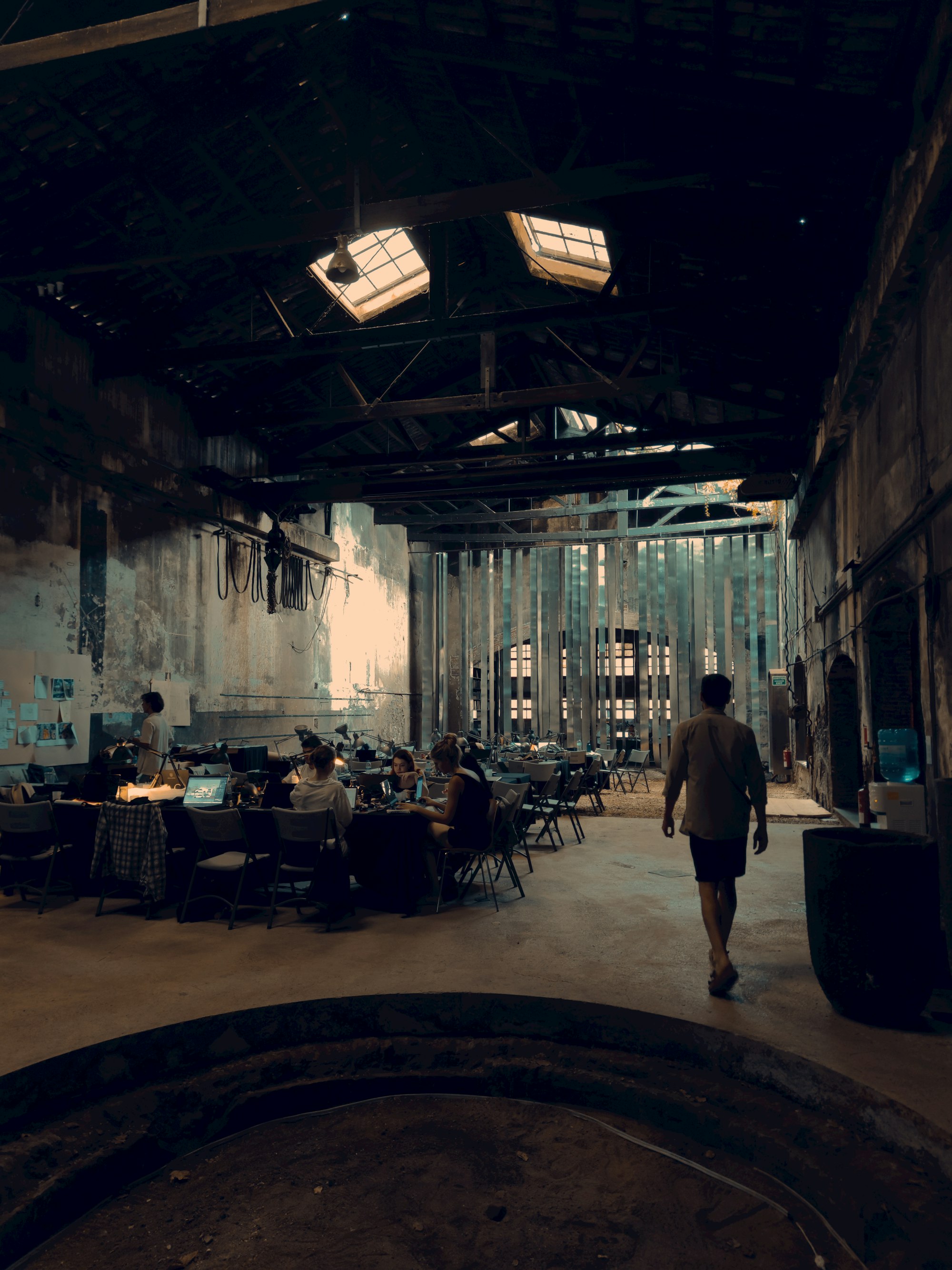People working at desks together inside a large, raw industrial hall